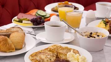A breakfast table with croissants, scrambled eggs, and a bowl of cereal.