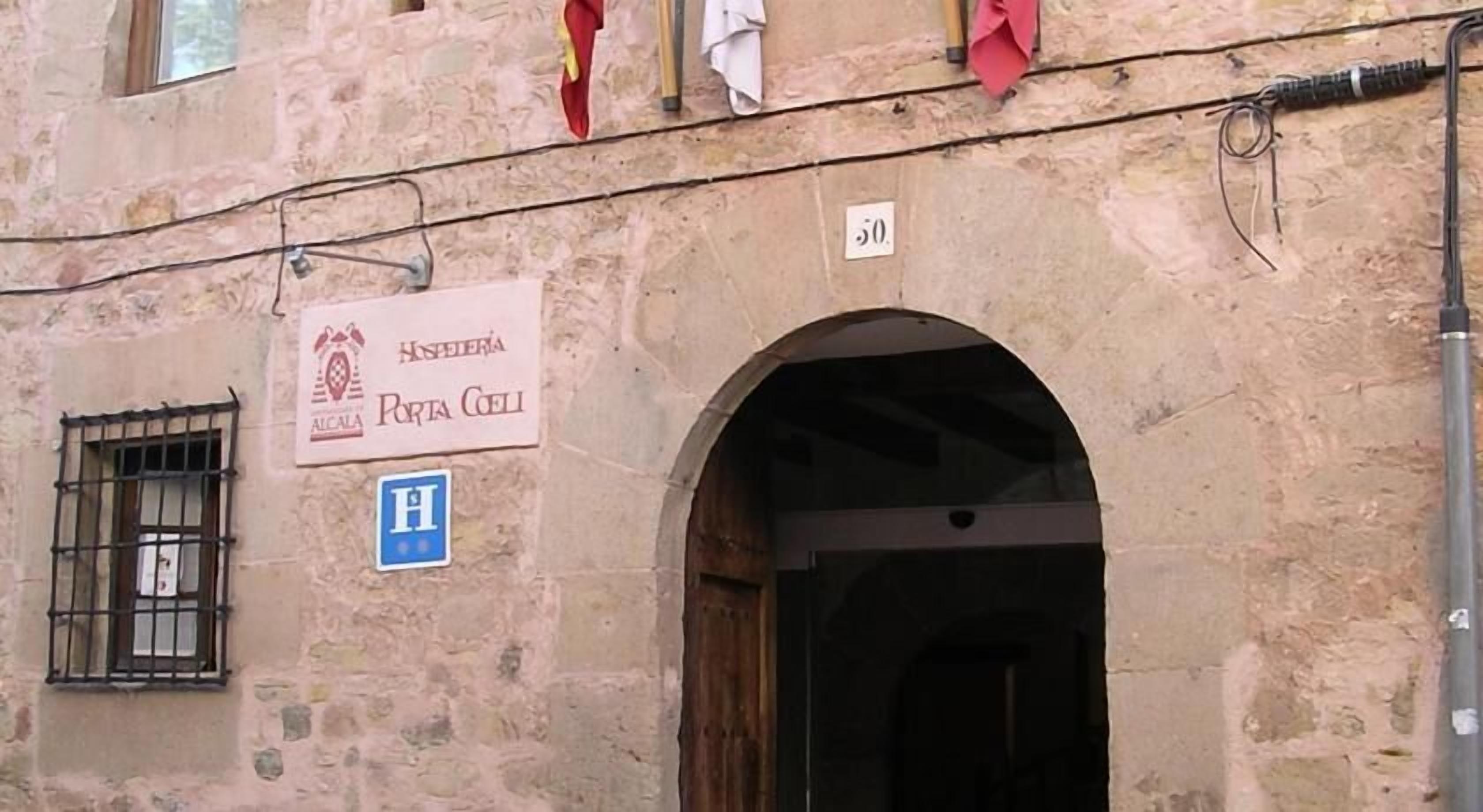 A stone building with a sign for 'Hospedaria Porta Coeli' and a hospital symbol.