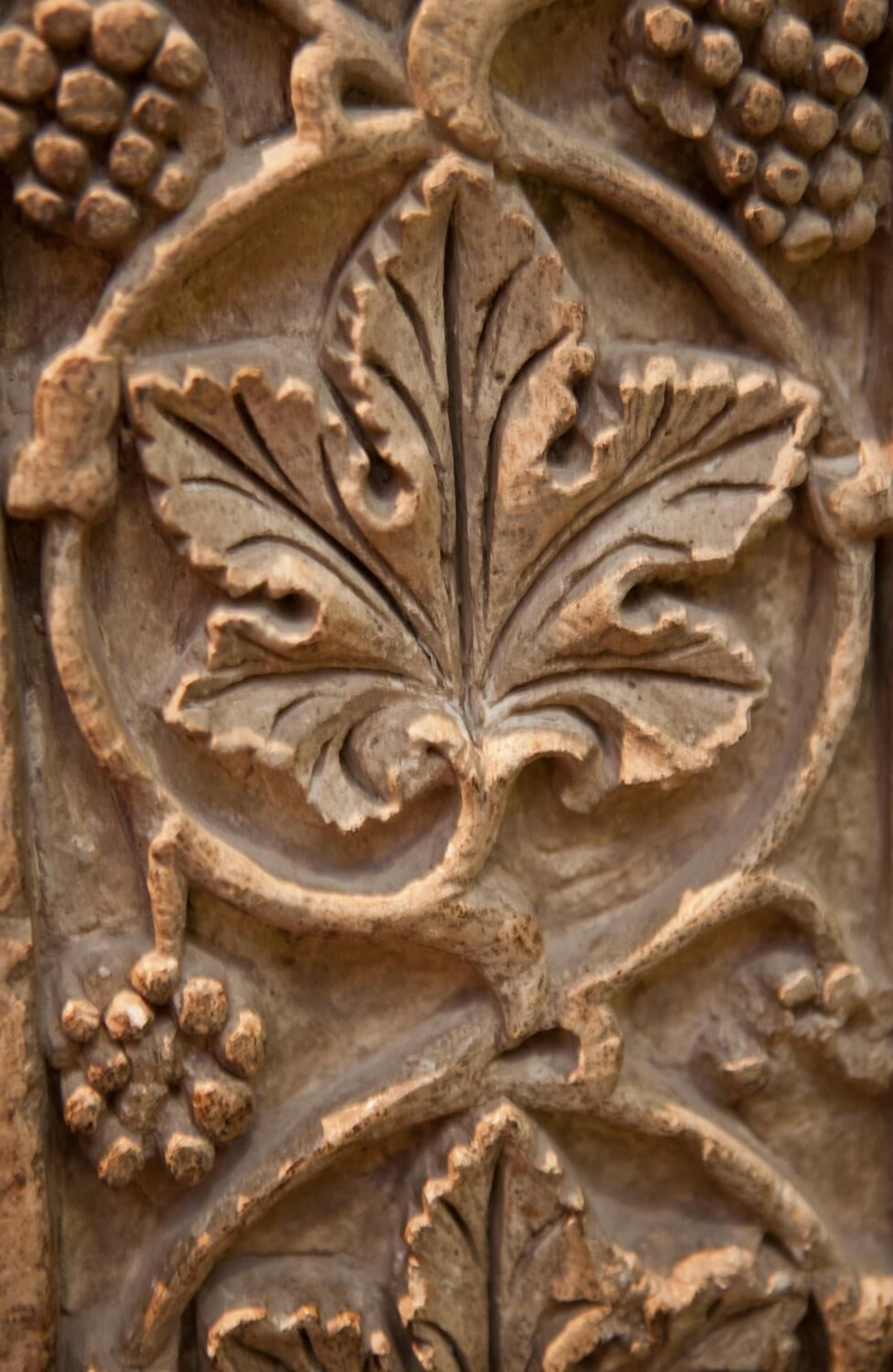 A detailed stone carving with a central leaf motif surrounded by smaller floral elements.