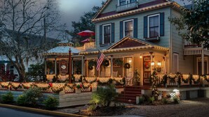 A two-story house with a porch decorated with Christmas lights and wreaths. - Cedar House Inn (St. Augustine)
