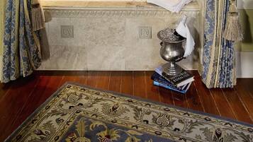 A luxurious bathroom with a marble bathtub, ornate curtains, a decorative rug, and a small shelf with toiletries.