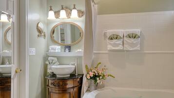 A bathroom with a sink, vanity, mirror, and bathtub.