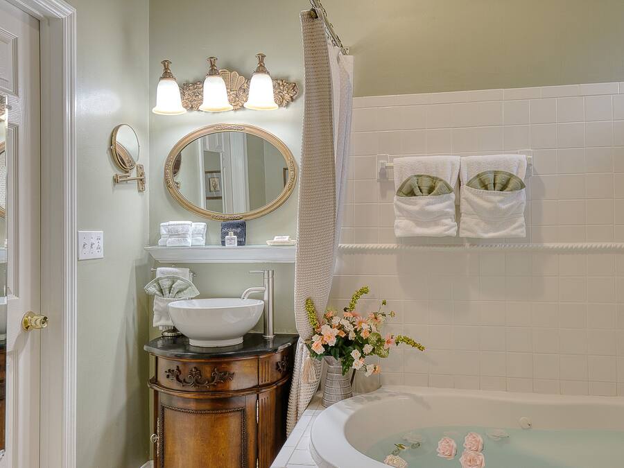 A bathroom with a sink, vanity, mirror, and bathtub.