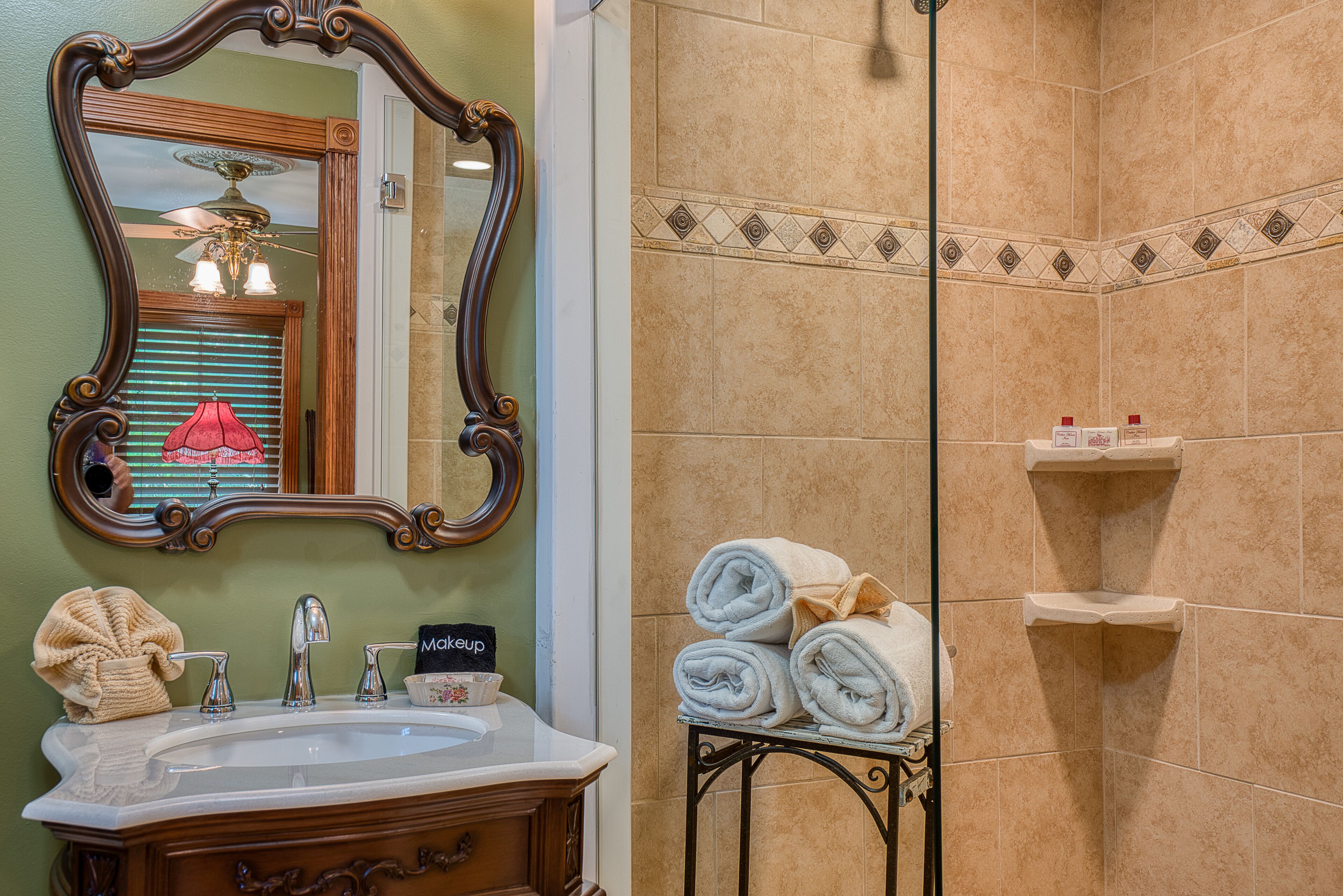 A bathroom with a vanity, a mirror, a towel rack, and a shower area.