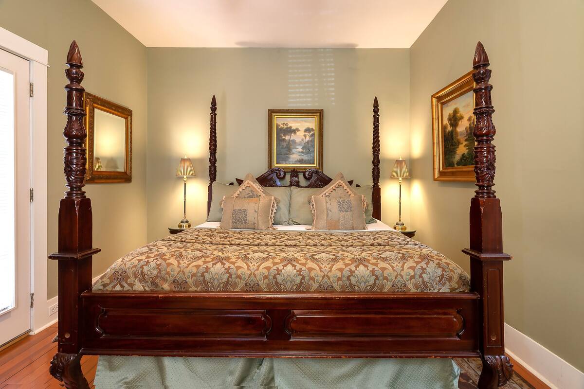 A large, ornate wooden bed with a detailed headboard, flanked by two tall, decorative columns.