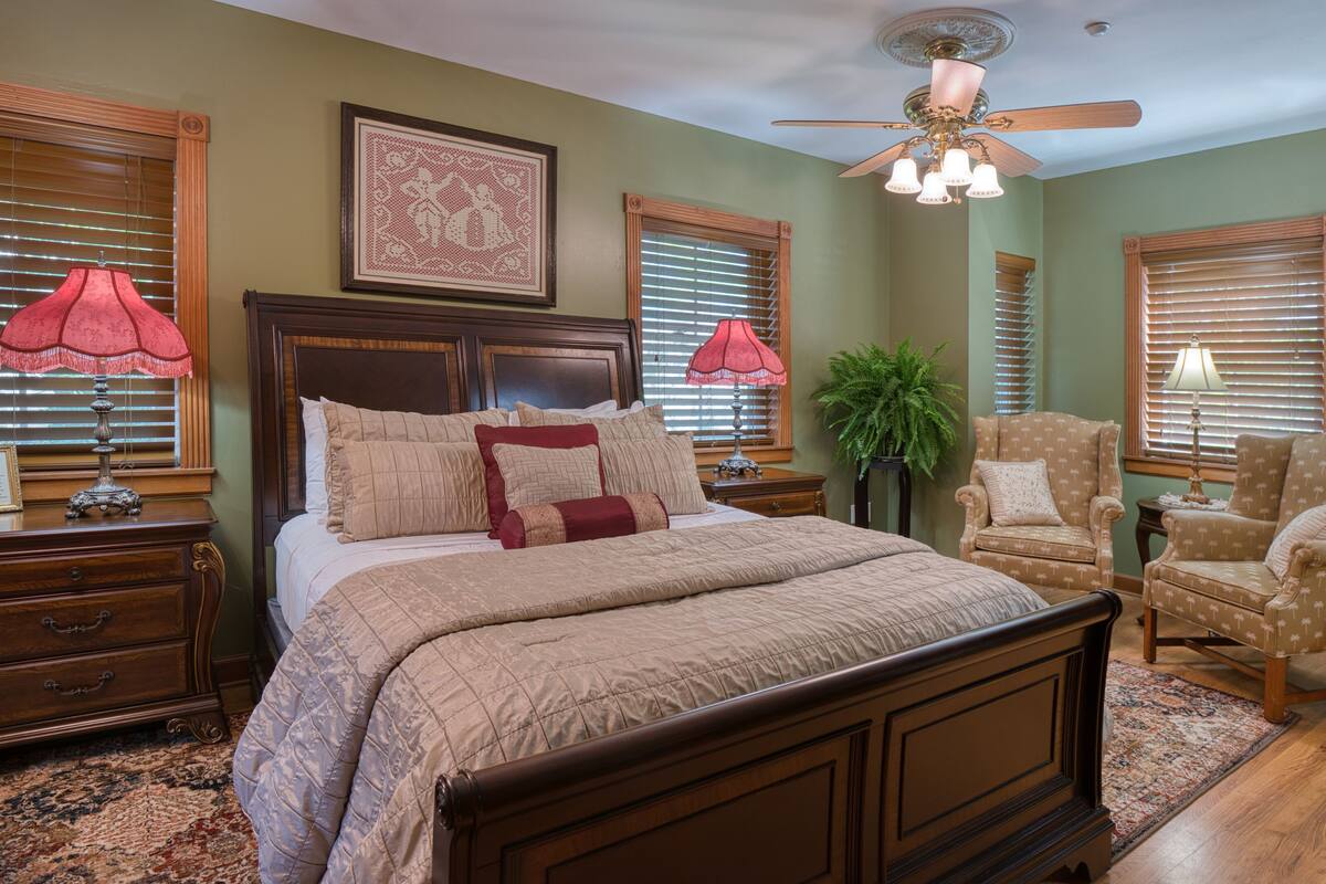 A bedroom with a large bed, two nightstands, a ceiling fan, and a chair.