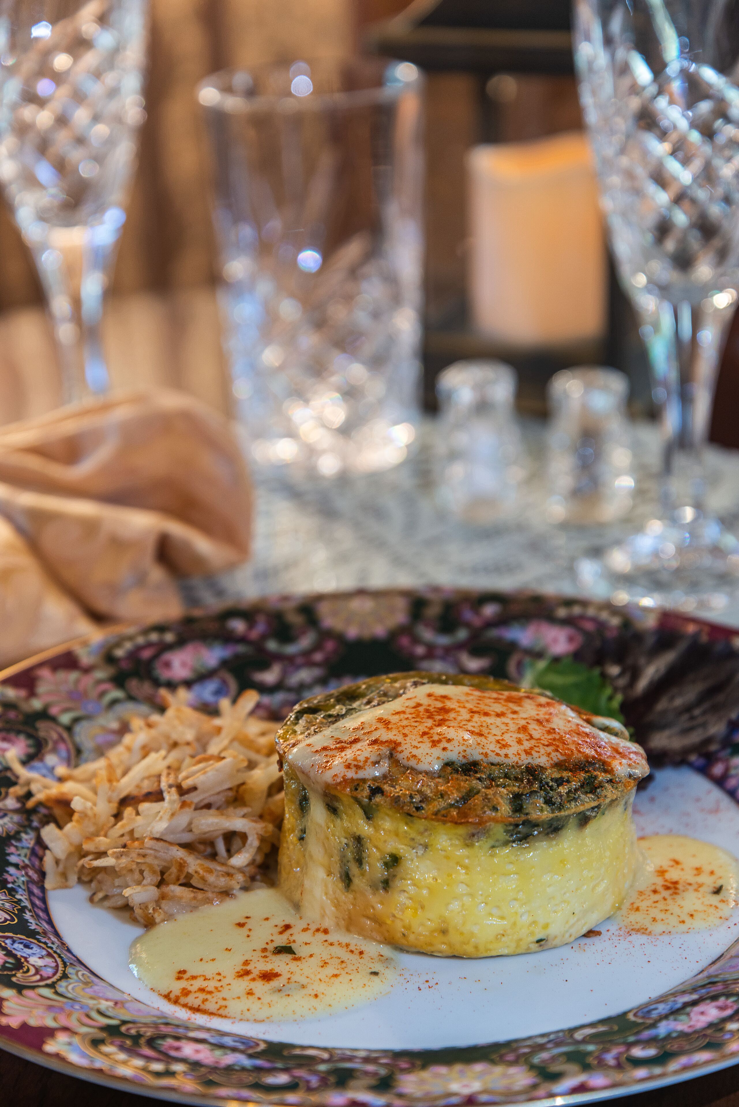Un plato de comida con un guiso cremoso, posiblemente una quiche, acompañado de carne desmenuzada y una salsa aparte.