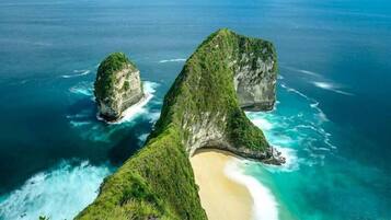 A coastal landscape with two prominent rock formations and a beach.