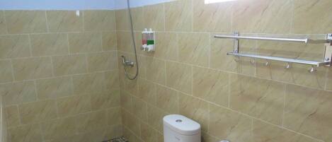 Une petite salle de bain comprenant des toilettes, une douche et un sèche-mains.