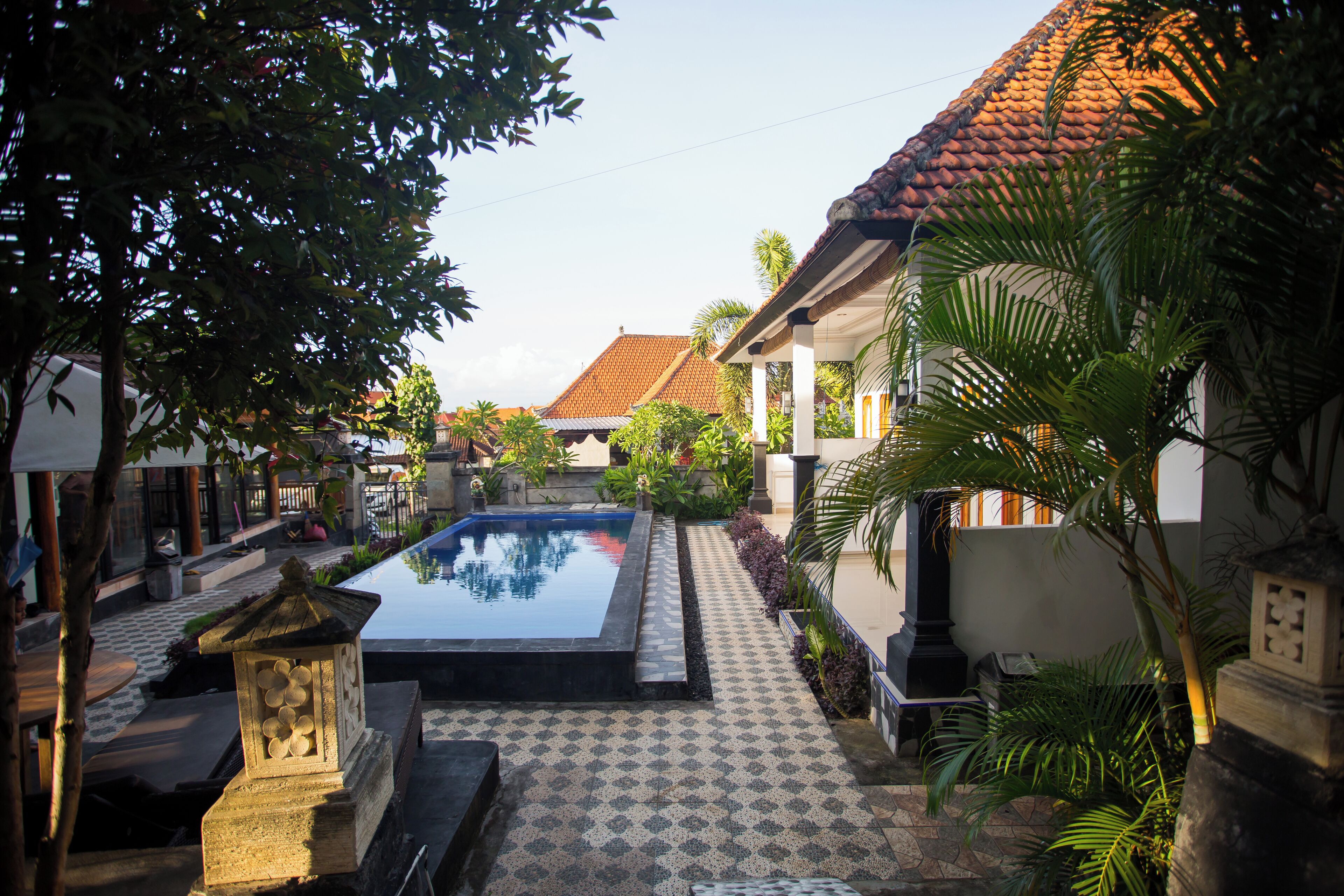 A courtyard with a swimming pool, tiled flooring, and surrounding greenery.