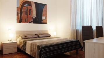 A bedroom with a bed, bedside tables, a desk, and a large painting on the wall.