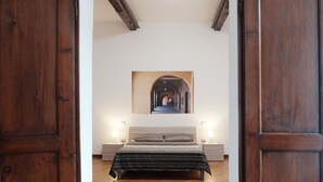 A bedroom with a bed, two bedside tables, a nightstand, and a wall-mounted picture.