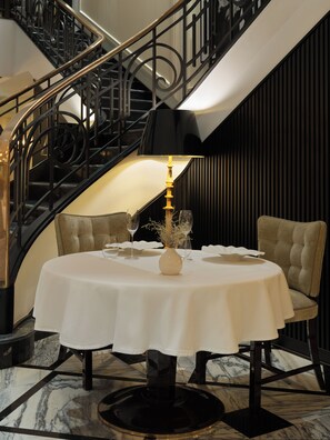 A dining table with a white tablecloth, a vase with branches, and wine glasses. - The One Monumental Palace (Porto)