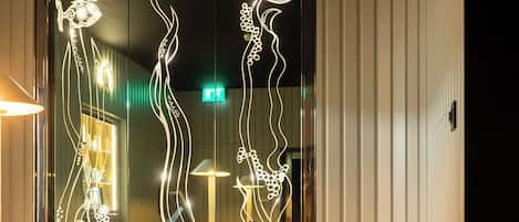Un interior moderno con un panel de vidrio decorativo, una silla y suelo de baldosas.