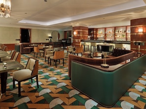 A bar area with a curved counter, multiple seating options including booths and tables, and a patterned carpet. - The One Monumental Palace (Porto)