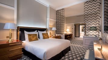 A hotel room with a large bed, two bedside tables, a desk, and a chair.
