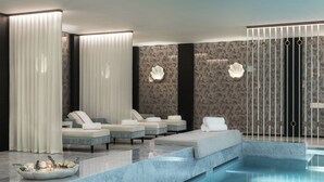 Un área de spa moderna con piscina, sillones de descanso y una recepción.