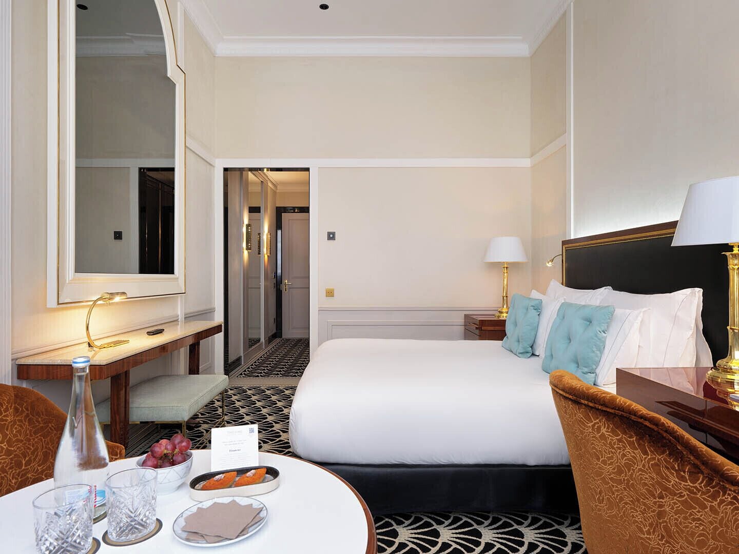A hotel room with a bed, bedside table, lamp, and a mirror.