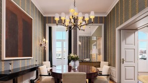 A dining area with a round table, four chairs, a chandelier, and a large mirror. - The One Monumental Palace (Porto)