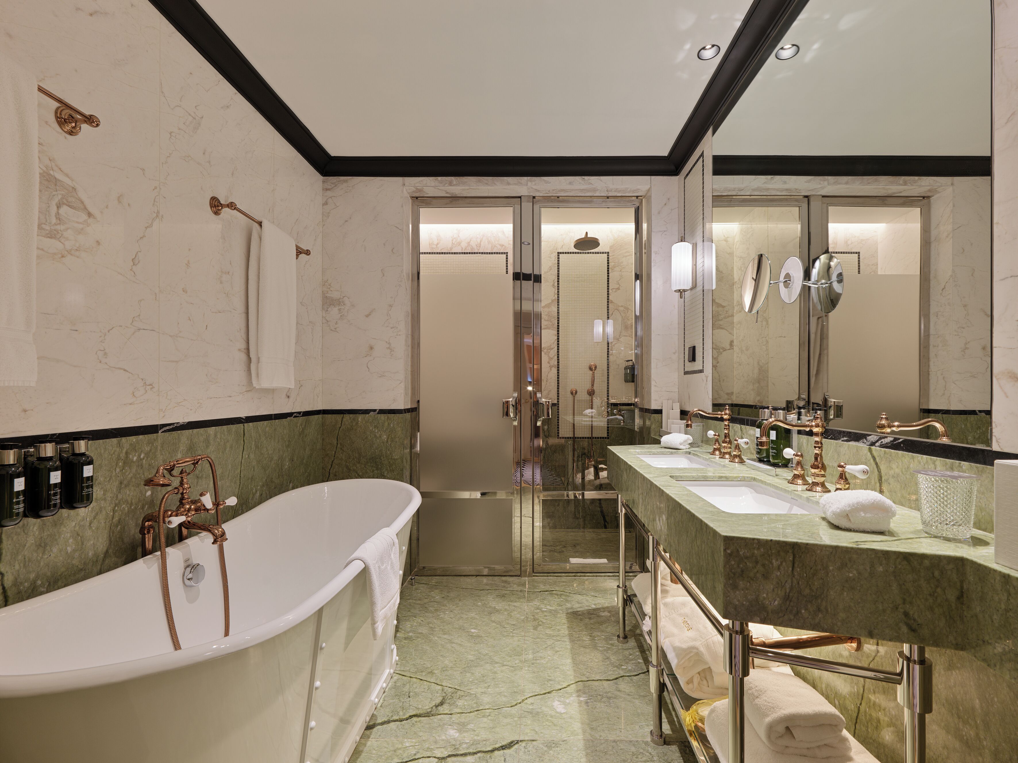 Un baño moderno con una bañera independiente, un lavamanos espacioso con doble lavabo y un espejo grande.