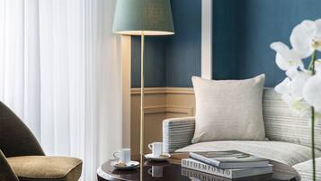 Una habitación con un sofá, una mesa de centro con libros, una lámpara y una ventana con cortinas.