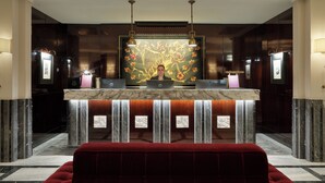A lobby with a reception desk, a large artwork, and a red sofa. - The One Monumental Palace (Porto)