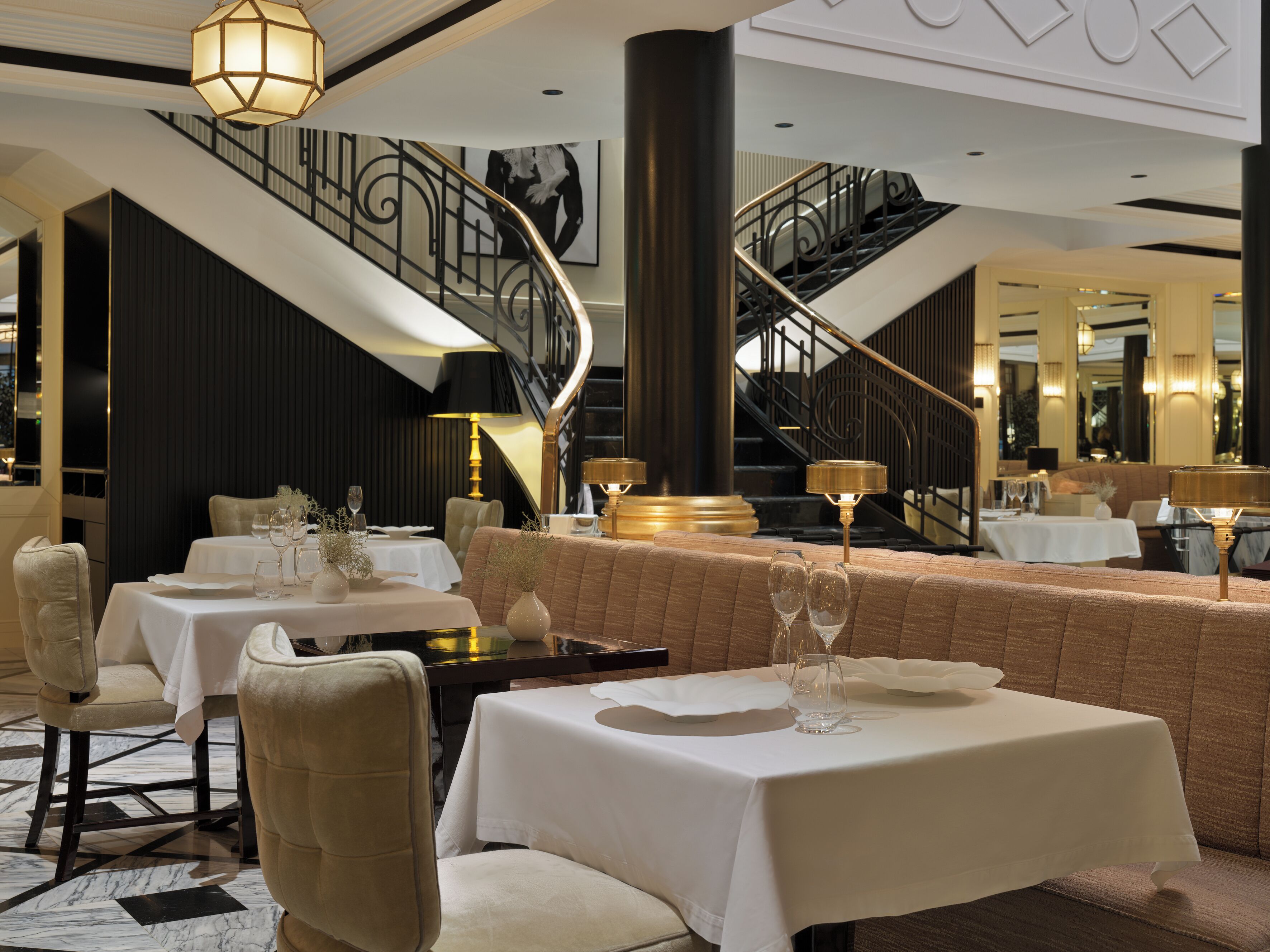 Un restaurante con varias mesas, sillas y una escalera.