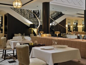 Un restaurante con varias mesas, sillas y una escalera.