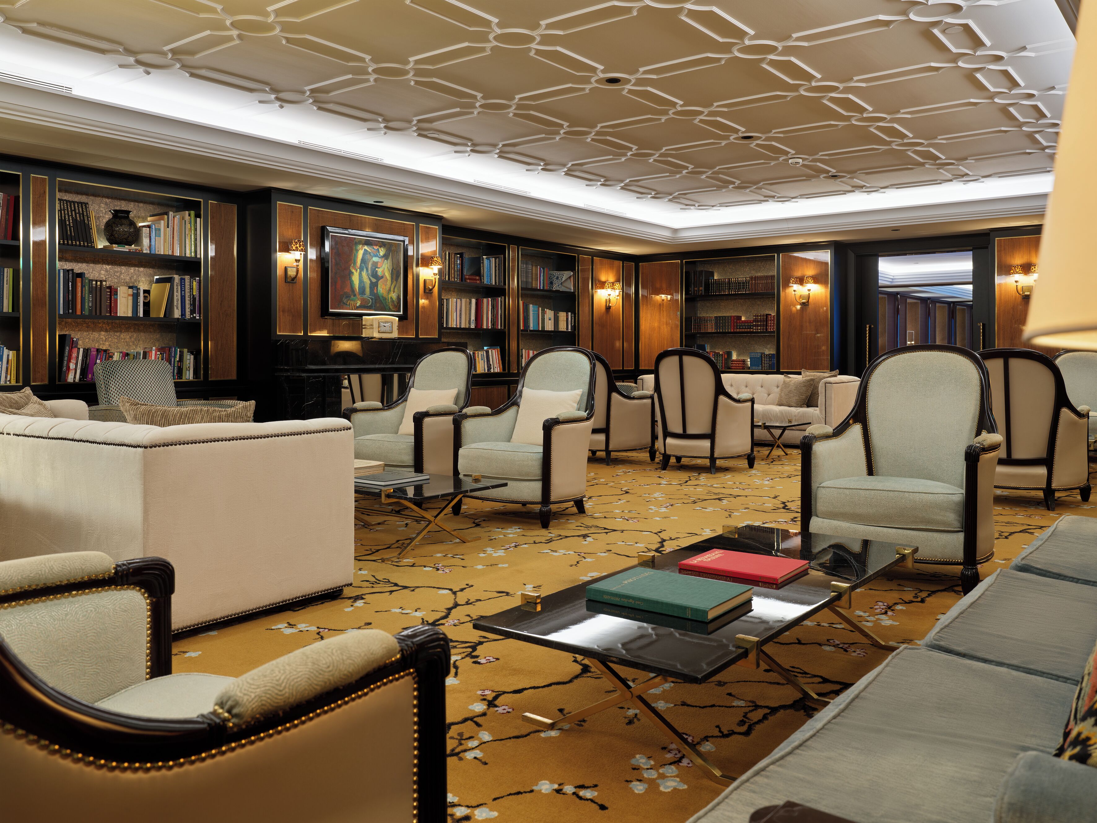 A library with bookshelves, seating, and a ceiling with a geometric pattern.