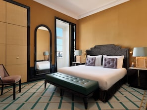 A hotel room with a large bed, a bench, a chair, a mirror, and two bedside tables with lamps. - The One Monumental Palace (Porto)