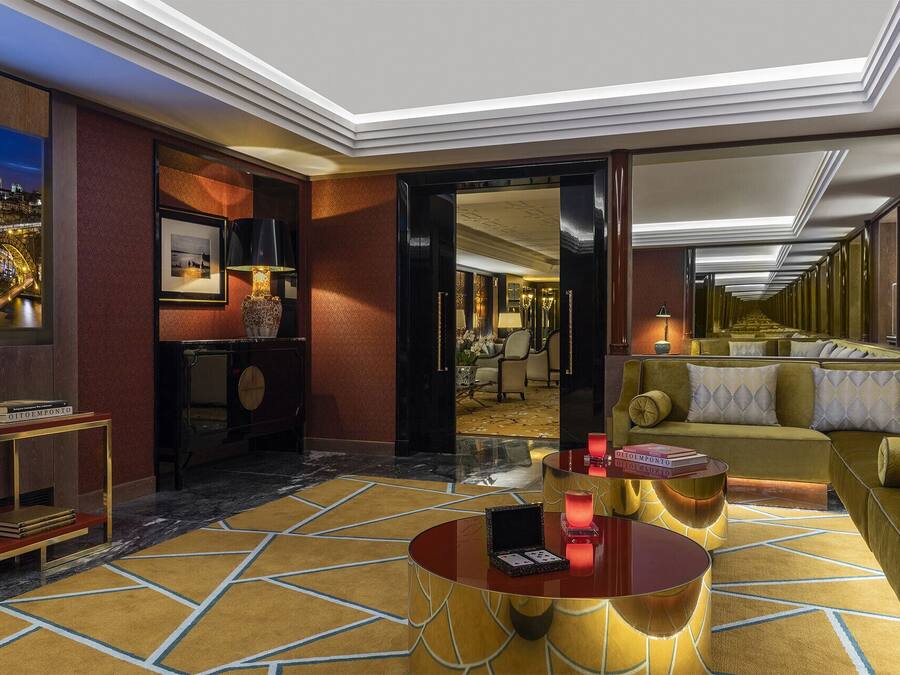 Un lobby de hotel lujoso con piso de mármol, una mesa redonda para café, un sofá y vista a la Torre Eiffel a través de un ventanal grande.