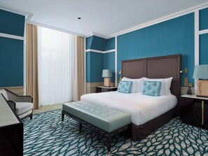 Una habitación de hotel con una cama grande, un banco, un escritorio y una silla.