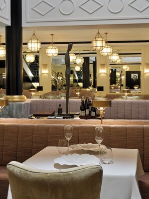 A restaurant interior with a seating area, tables, and hanging light fixtures. - The One Monumental Palace (Porto)