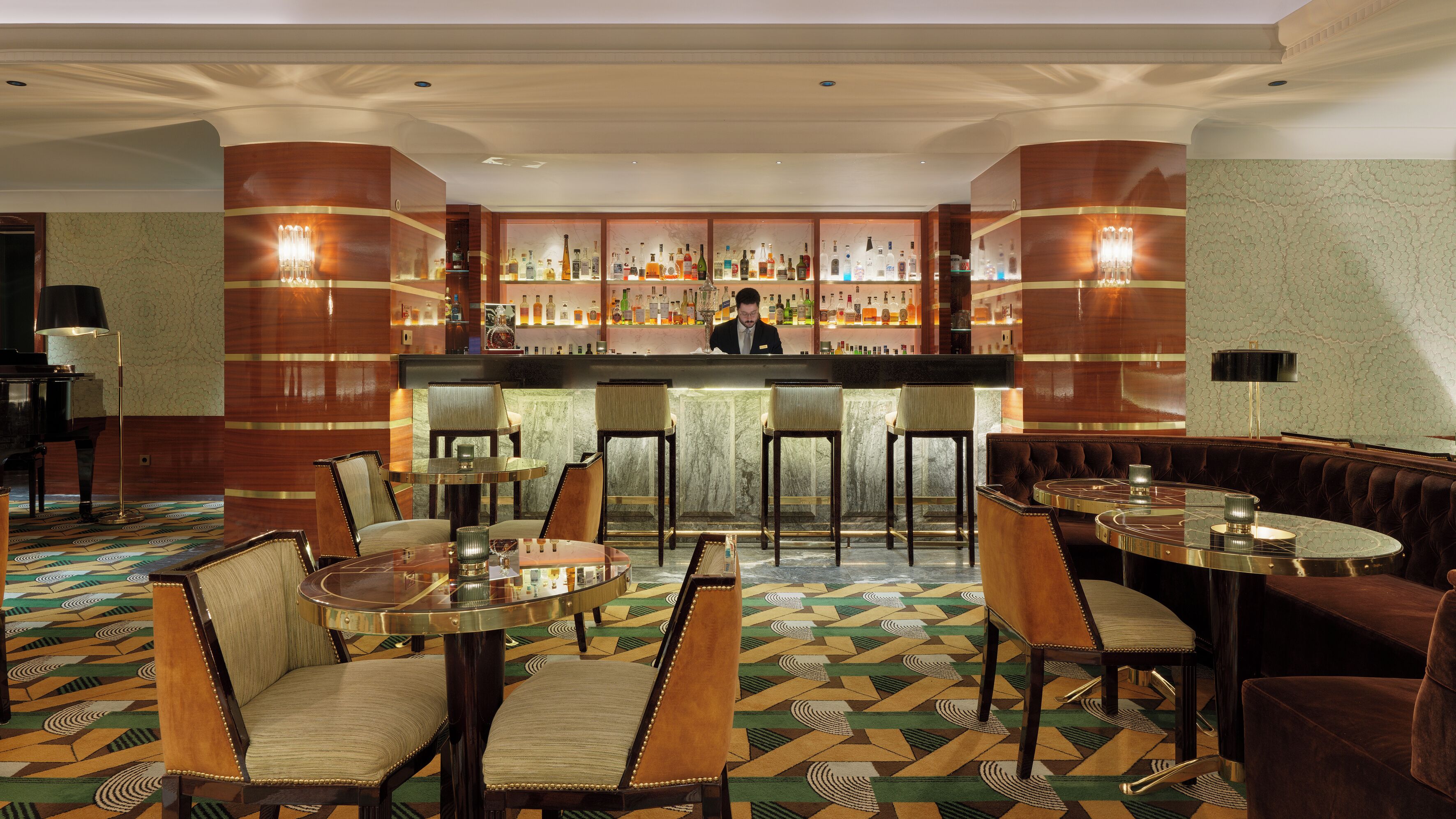 A bar area with a bartender, bar stools, and a seating area with round tables and chairs.