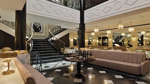 Un vestíbulo de hotel con una escalera, un área de descanso y un bar.