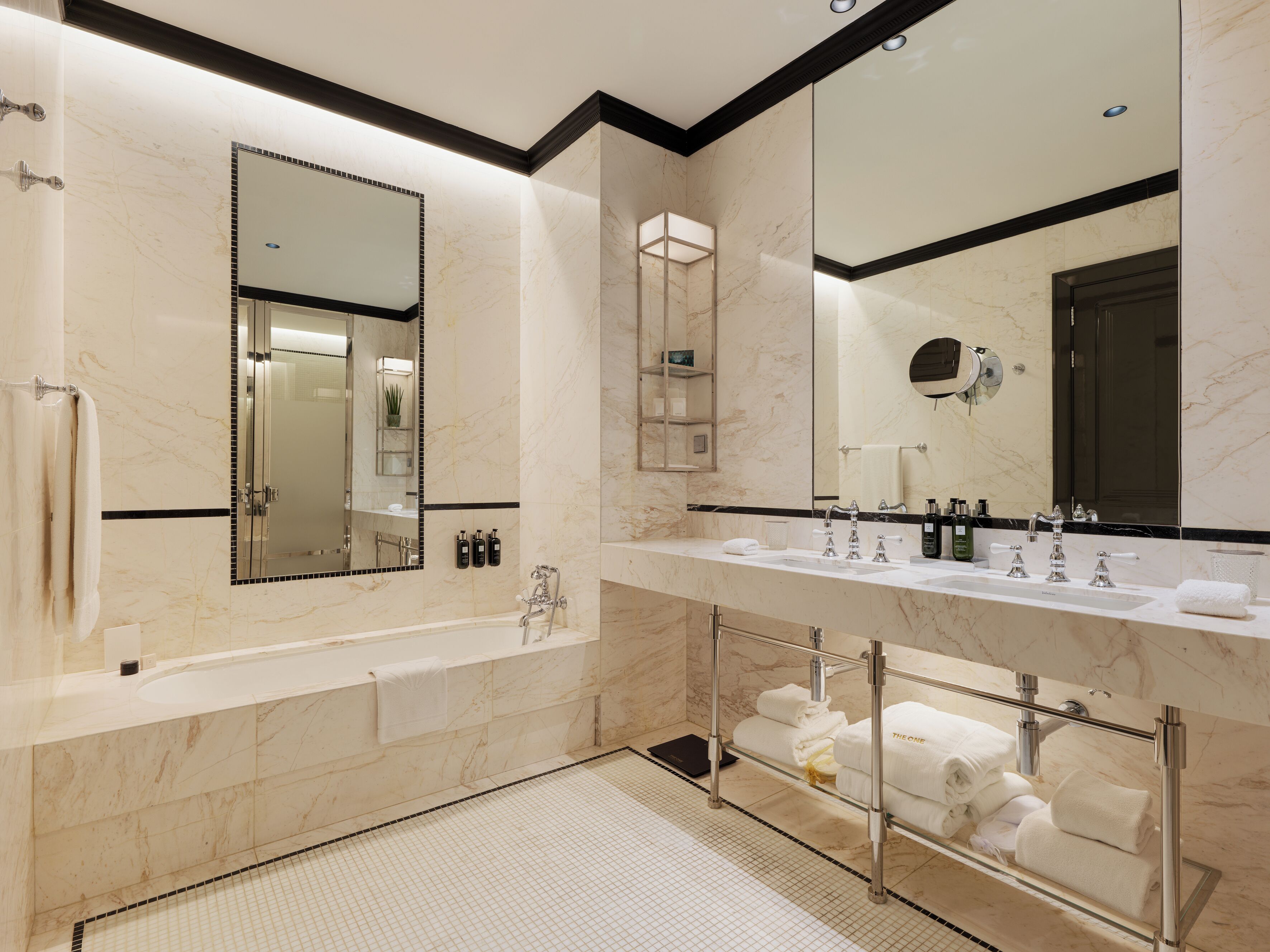 Un baño moderno con un espejo grande, lavamanos dobles, una bañera y cabina de ducha de vidrio.