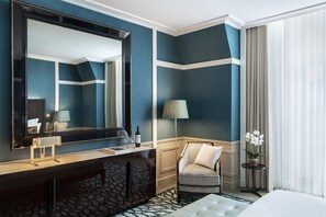 A hotel room with a large mirror, a vanity with a lamp, a chair, a bedside table with a vase of flowers, and a bed. - The One Monumental Palace (Porto)