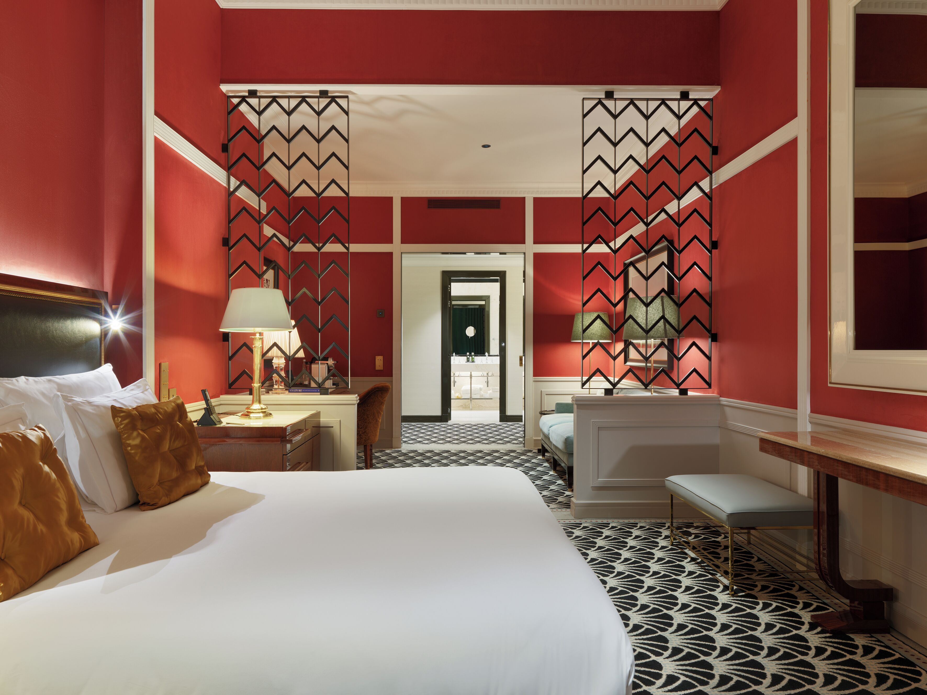Una habitación de hotel con una cama grande, un escritorio, una silla y un tocador con espejo.