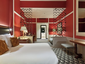 A hotel room with a large bed, a desk, a chair, and a vanity with a mirror. - The One Monumental Palace (Porto)