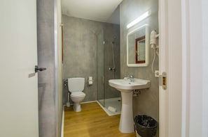 A bathroom with a glass shower enclosure, a white pedestal sink, and a toilet. - Apartamentos Sol Y Mar Menorca (Ciutadella de Menorca)