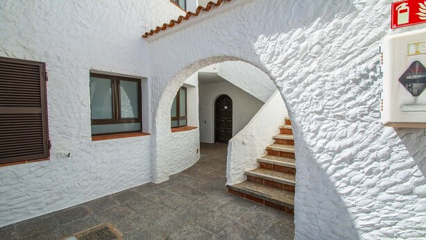 A narrow corridor with white walls and a tiled floor leading to a staircase. - Apartamentos Sol Y Mar Menorca (Ciutadella de Menorca)