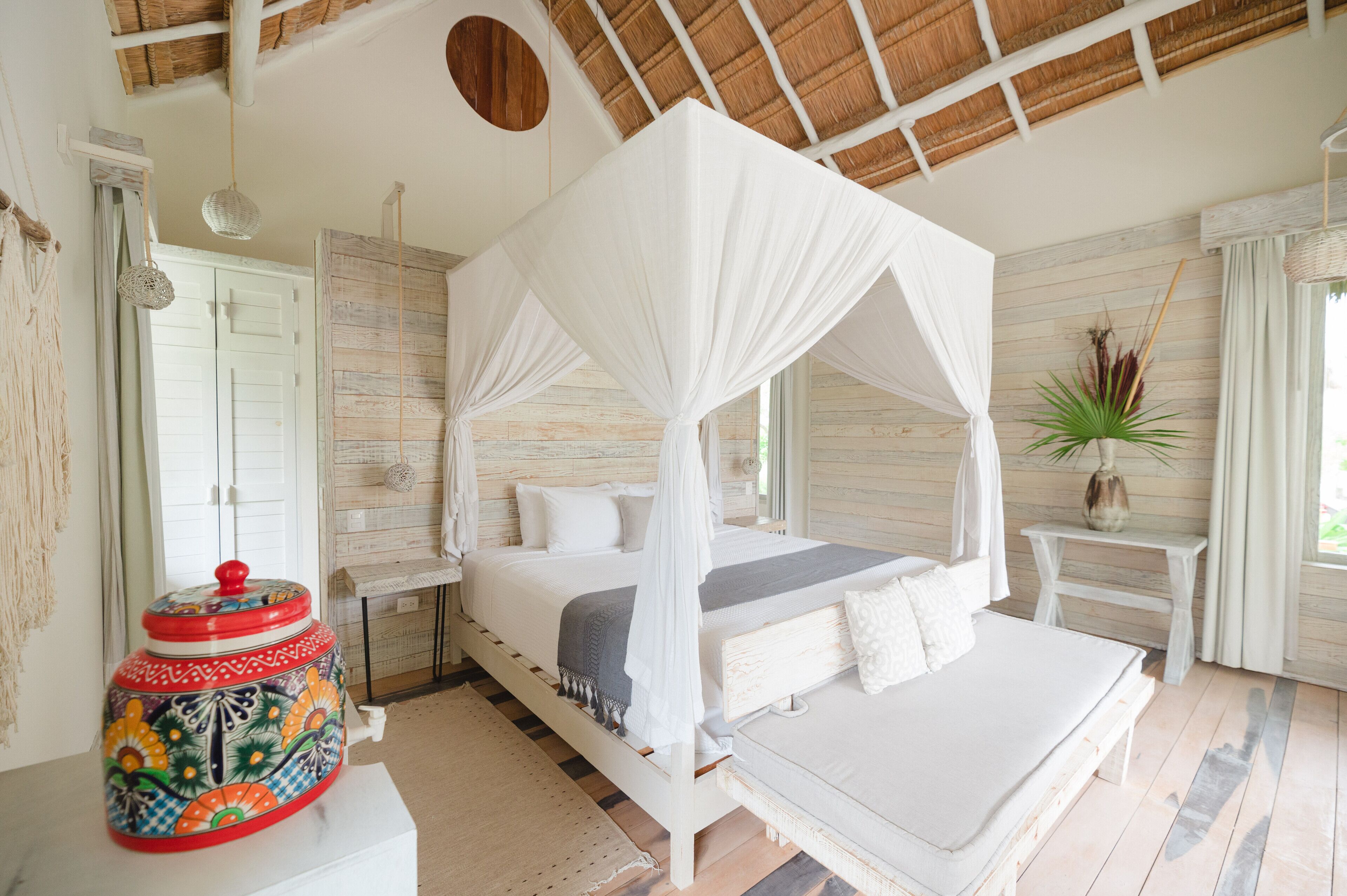 A bedroom with a four-poster bed, a bedside table, a nightstand, and a decorative vase.