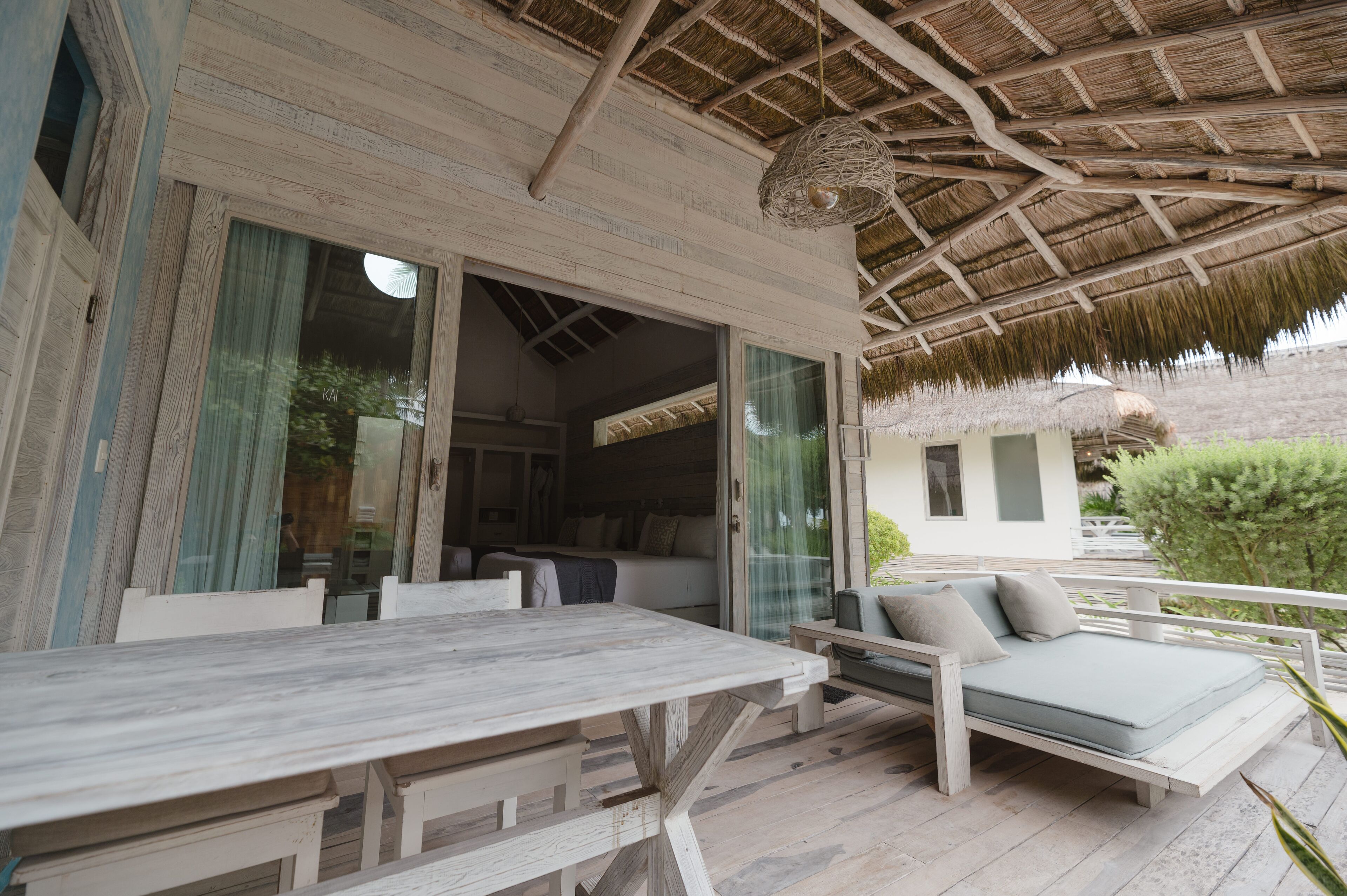 An outdoor seating area with a table and a sofa, a covered patio, and a view of the interior.