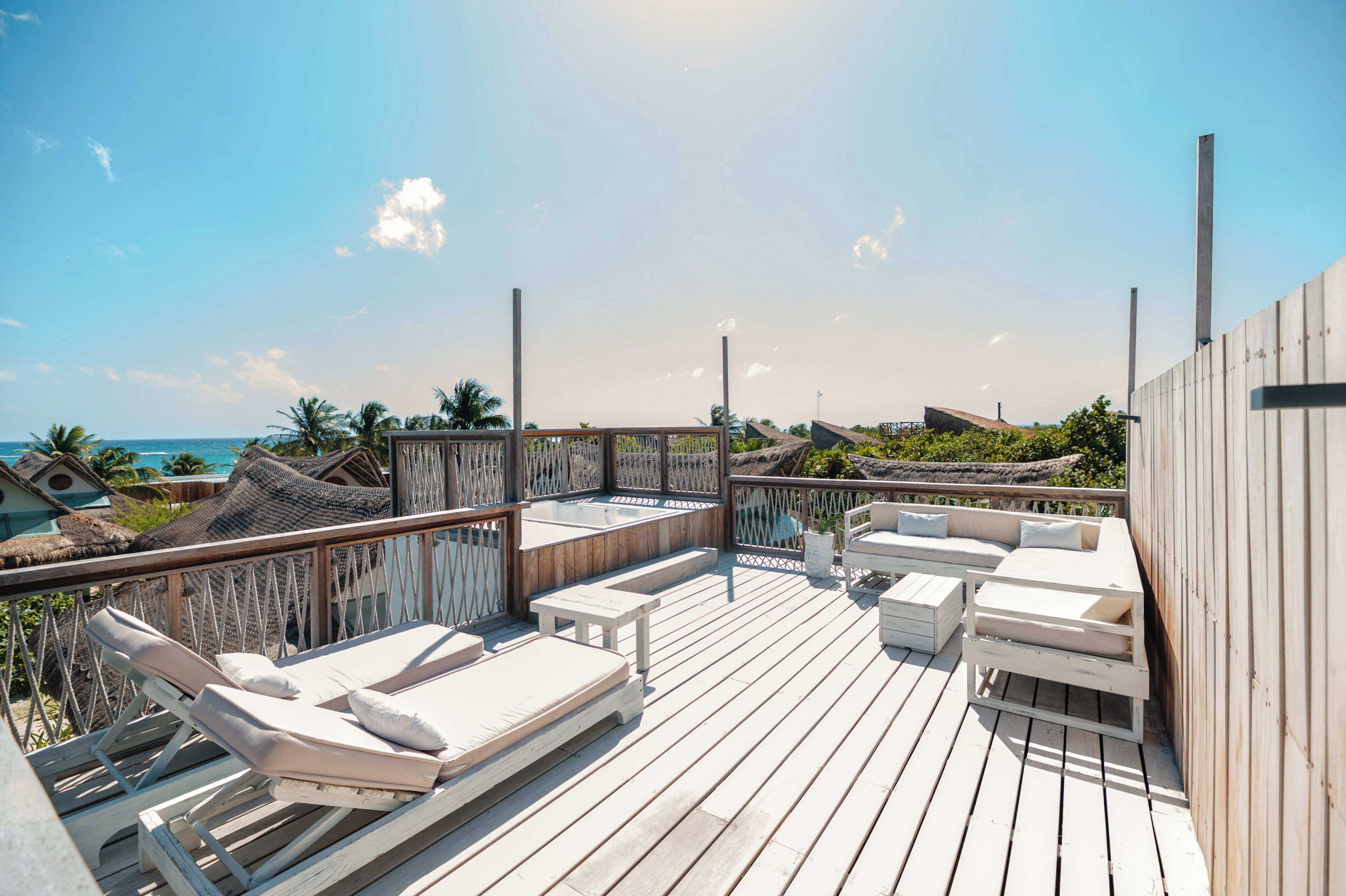 Eine Holzterrasse mit Liegestühlen und einer Sitzecke mit Blick auf den Strand.