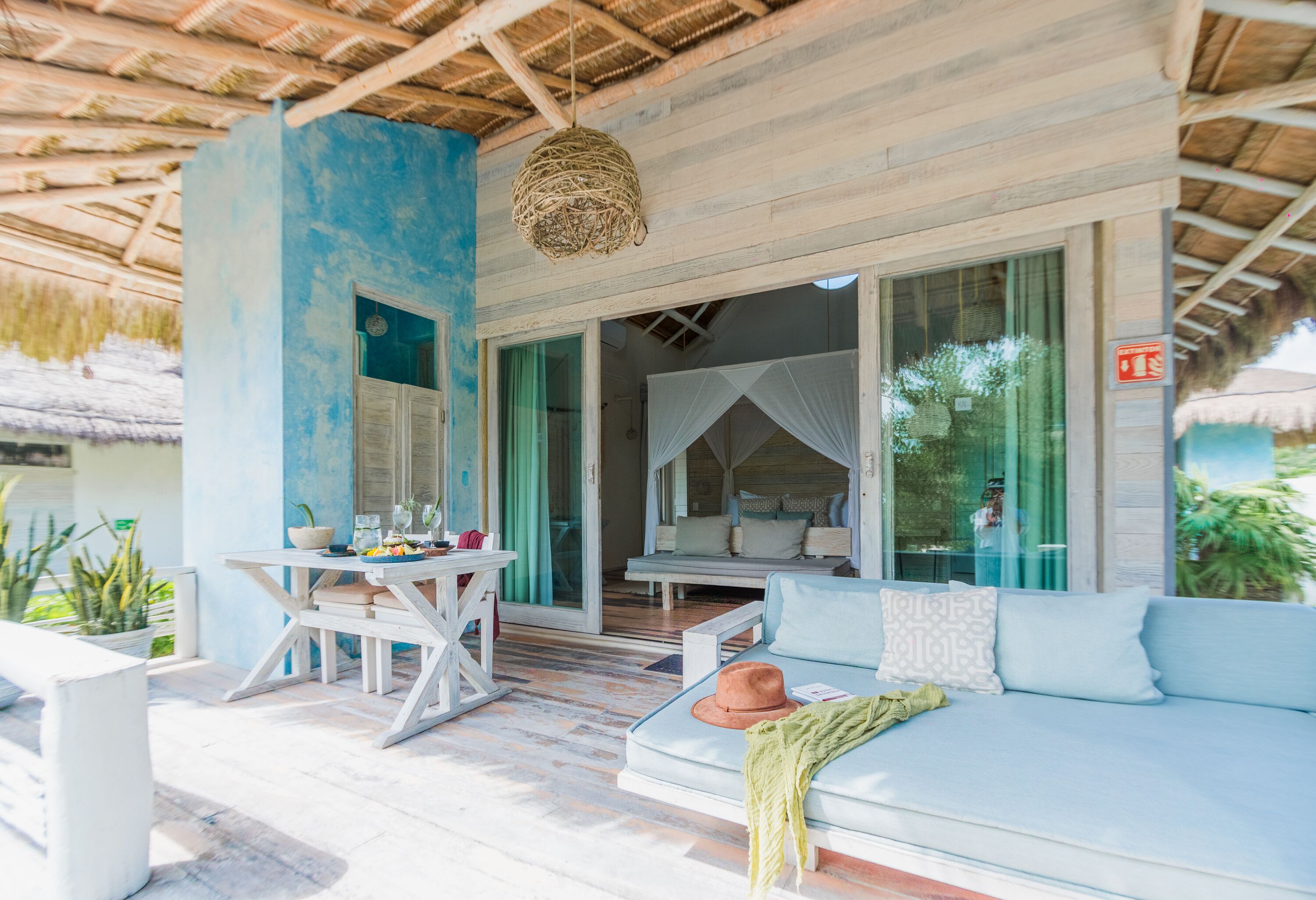 A room with a blue wall, a white sofa, a table with chairs, and a hanging light fixture.