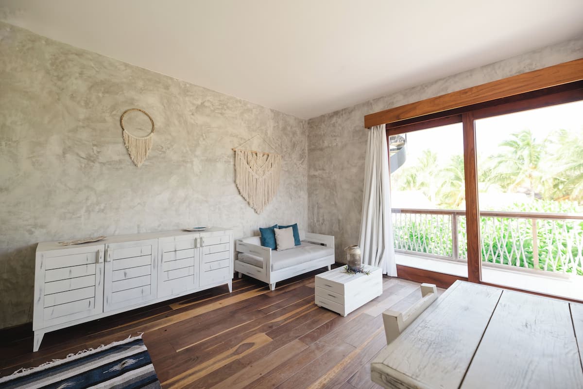 A room with a white sofa, a wooden coffee table, a white cabinet, and a macrame wall hanging.