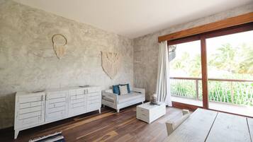 A room with a white sofa, a wooden coffee table, a white cabinet, and a macrame wall hanging.