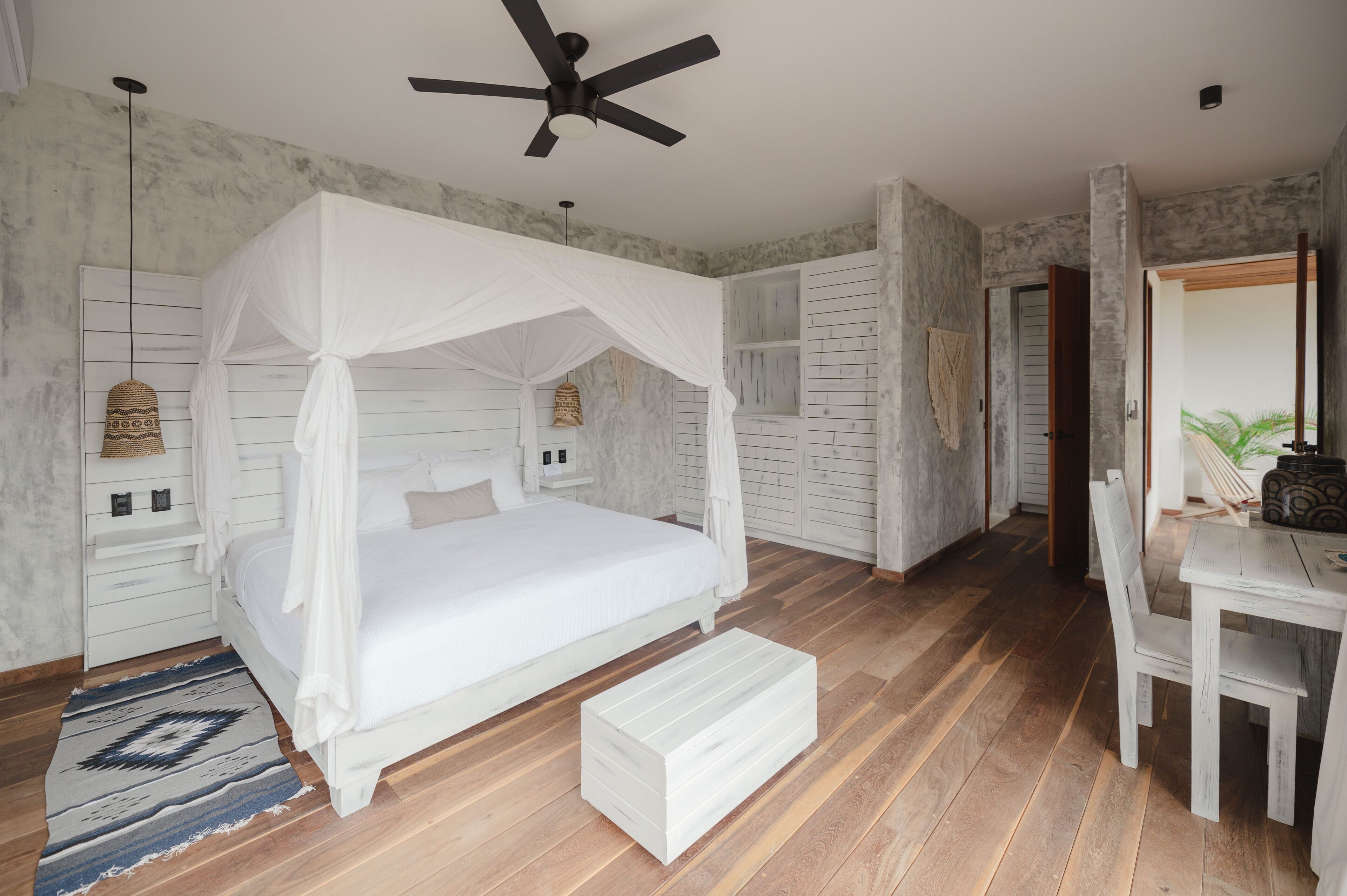 A bedroom with a canopy bed, a desk, and a chair.