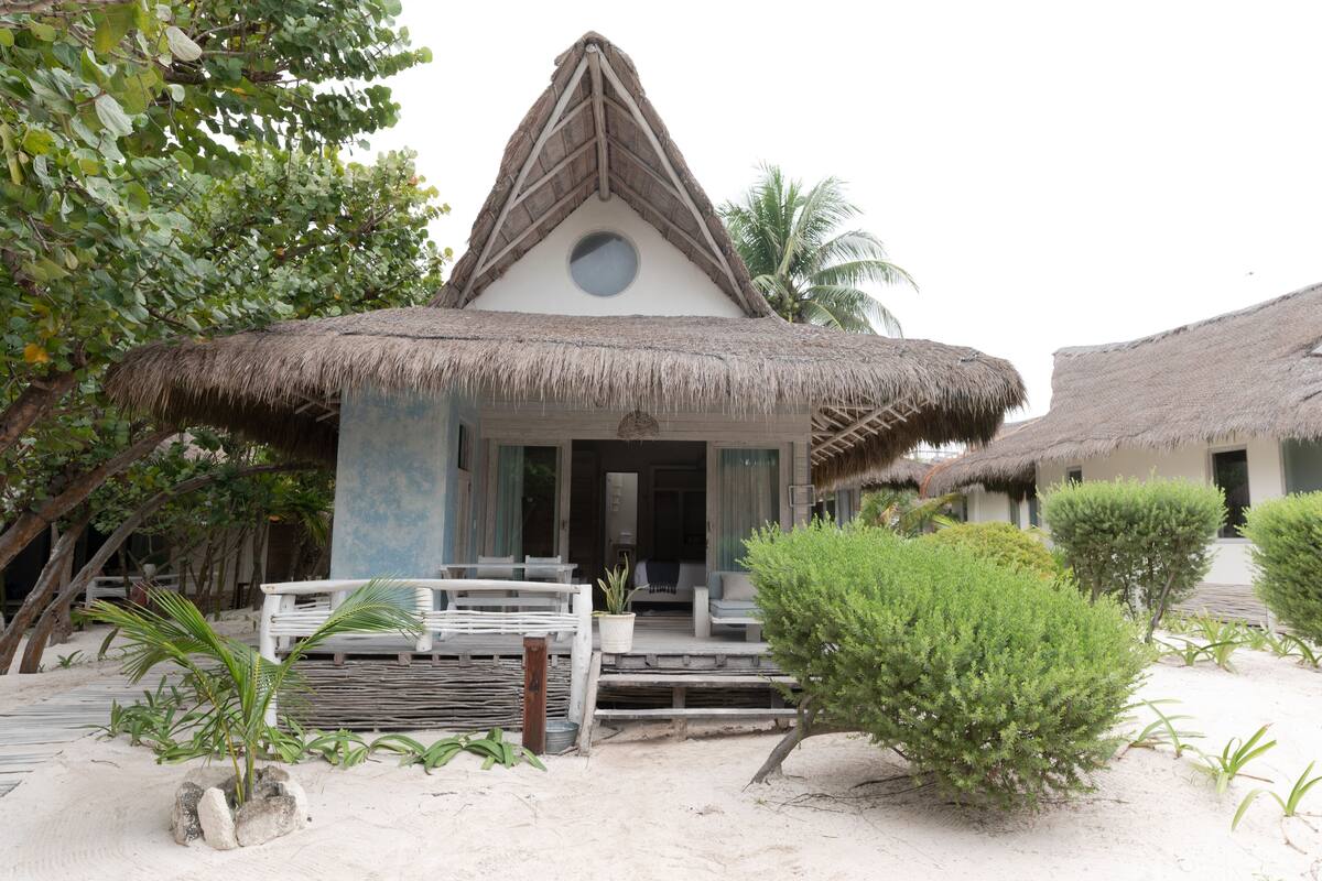 A thatched-roof building with a porch and steps leading to the entrance.