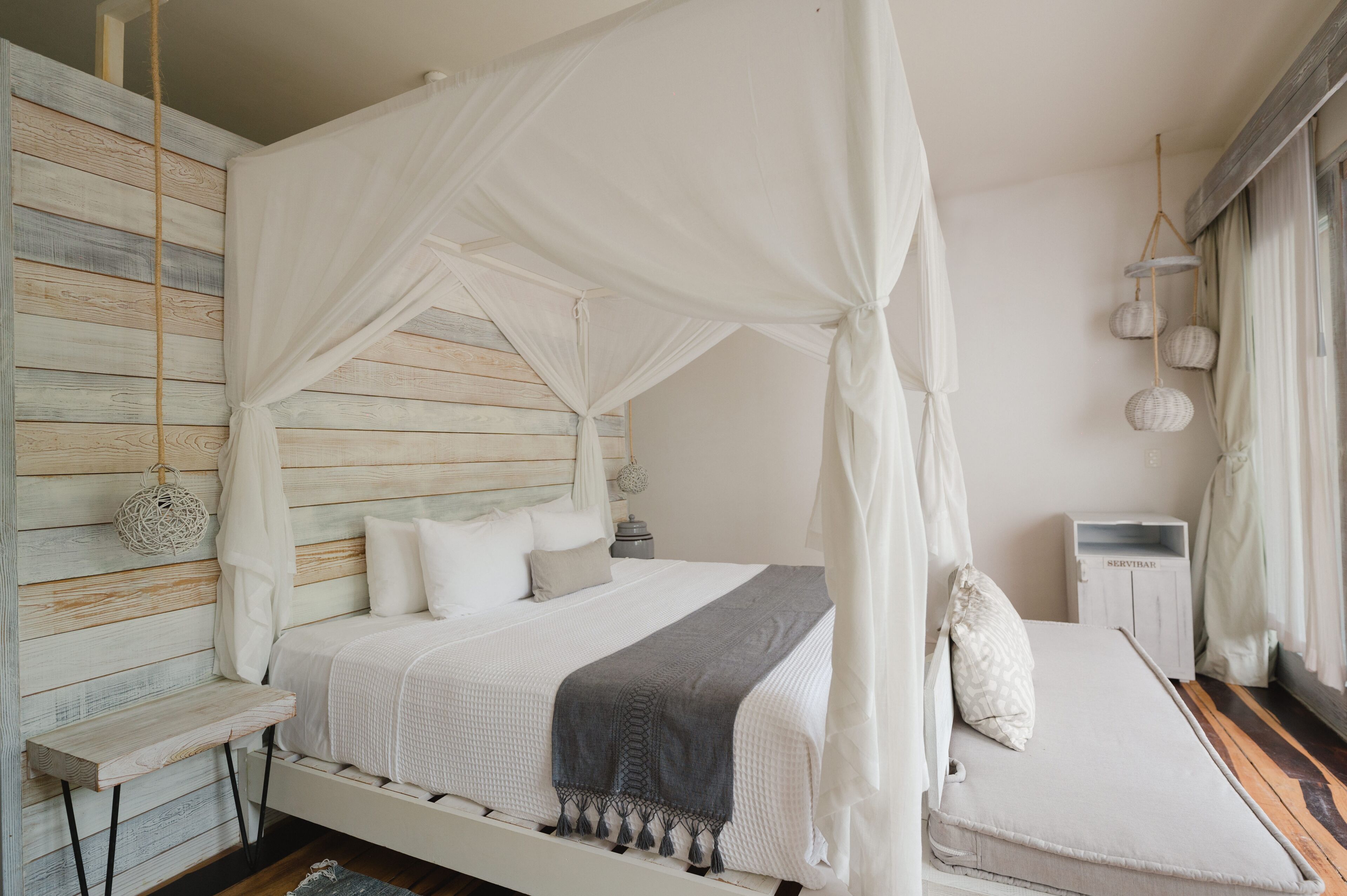 A bed with a canopy, a bedside table, and a nightstand.